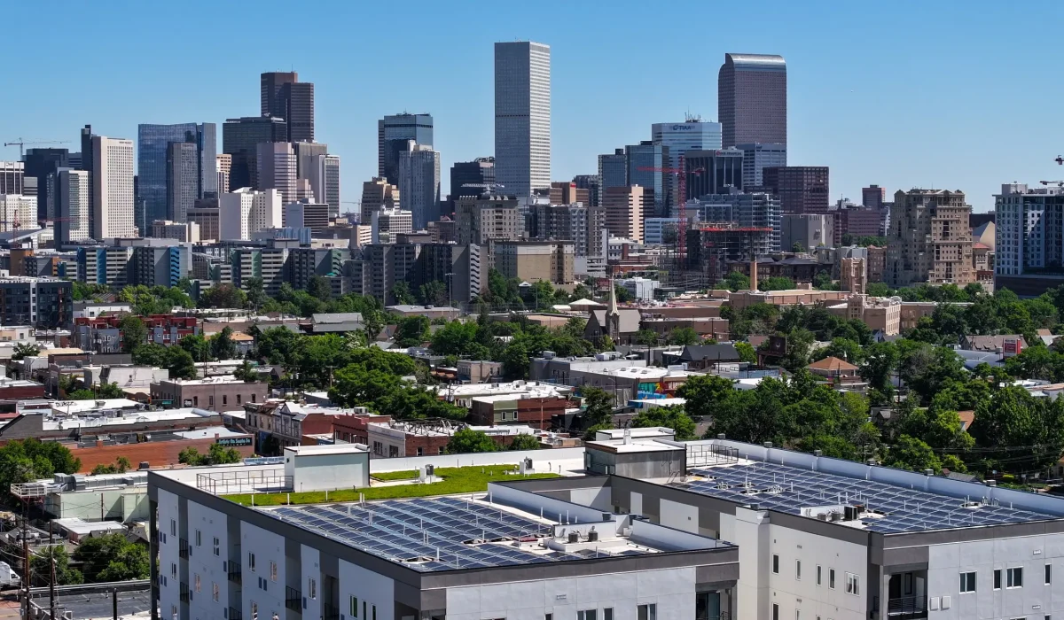 Why Selecting a Qualified Commercial Roofing Company is Crucial. View of Denver's downtown skyline with solar panels installed on rooftops, showcasing the city's blend of urban living and sustainable energy solutions.