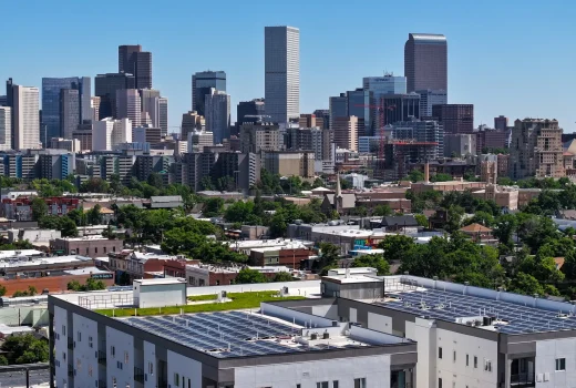 Why Selecting a Qualified Commercial Roofing Company is Crucial. View of Denver's downtown skyline with solar panels installed on rooftops, showcasing the city's blend of urban living and sustainable energy solutions.
