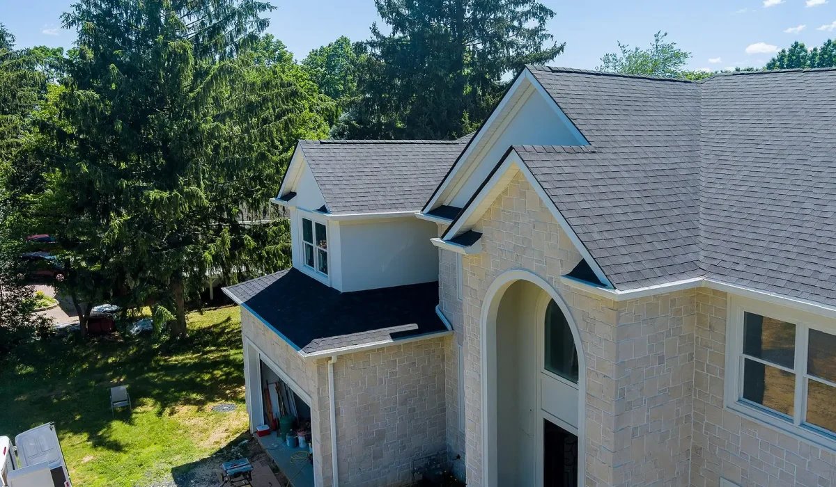 Why Are Insurance Companies Pulling Out of Some States? A beautiful two-story home showcasing a freshly installed gray shingle roof surrounded by lush greenery and trees.