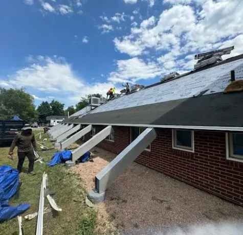 Colorado's Weather Extremes Take a Toll on Your Roof. Roofing professionals installing new shingles on a commercial building with visible underlayment under a sunny sky.