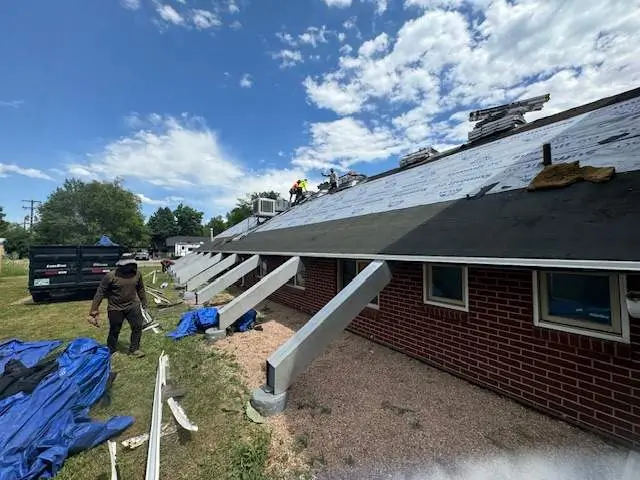 Colorado's Weather Extremes Take a Toll on Your Roof. Roofing professionals installing new shingles on a commercial building with visible underlayment under a sunny sky.