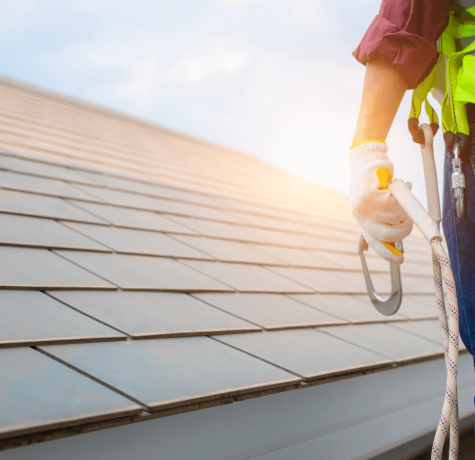 Roofer with safety harness inspecting residential shingle roof for certification