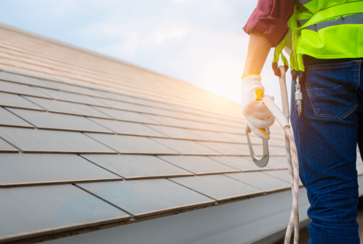 Roofer with safety harness inspecting residential shingle roof for certification