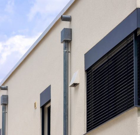 Properly sealed roof scupper draining water off flat roof to maintain compliance