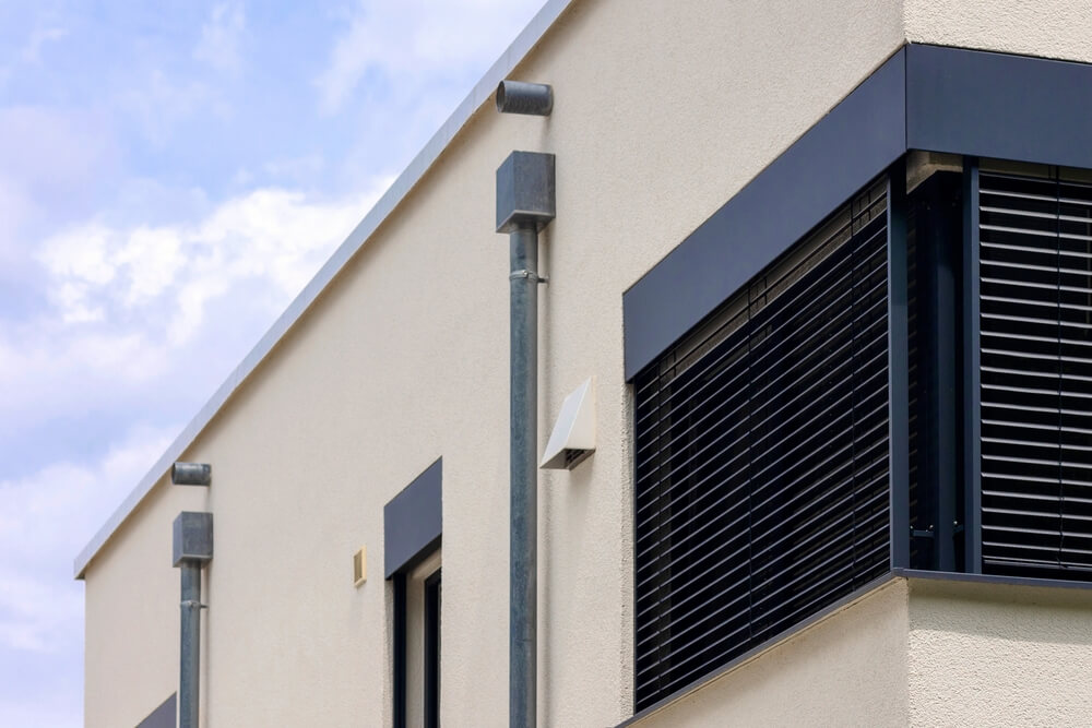 Properly sealed roof scupper draining water off flat roof to maintain compliance