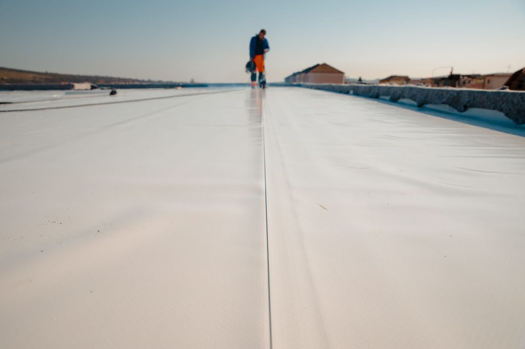 Denver roofing expert inspecting TPO membrane on a commercial flat roof.