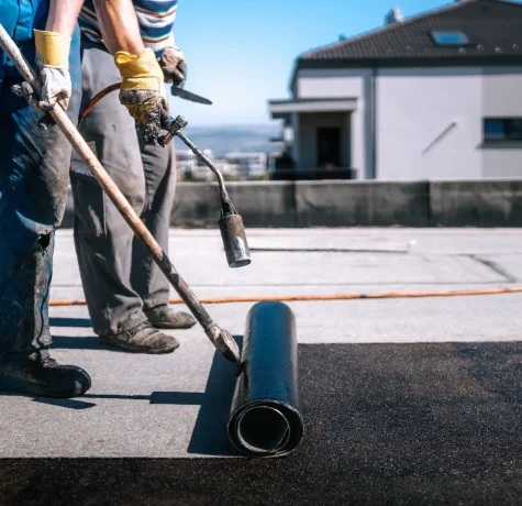 Contractor applying waterproof roof coating to a commercial building in Denver