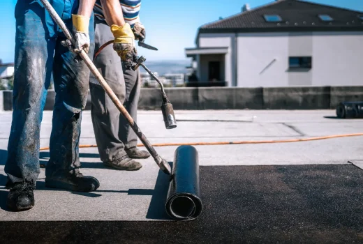 Contractor applying waterproof roof coating to a commercial building in Denver