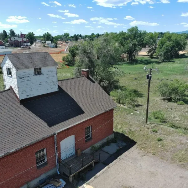 Side aerial of DHS Building 87 showing the completed shingle roof and historic brick exterior